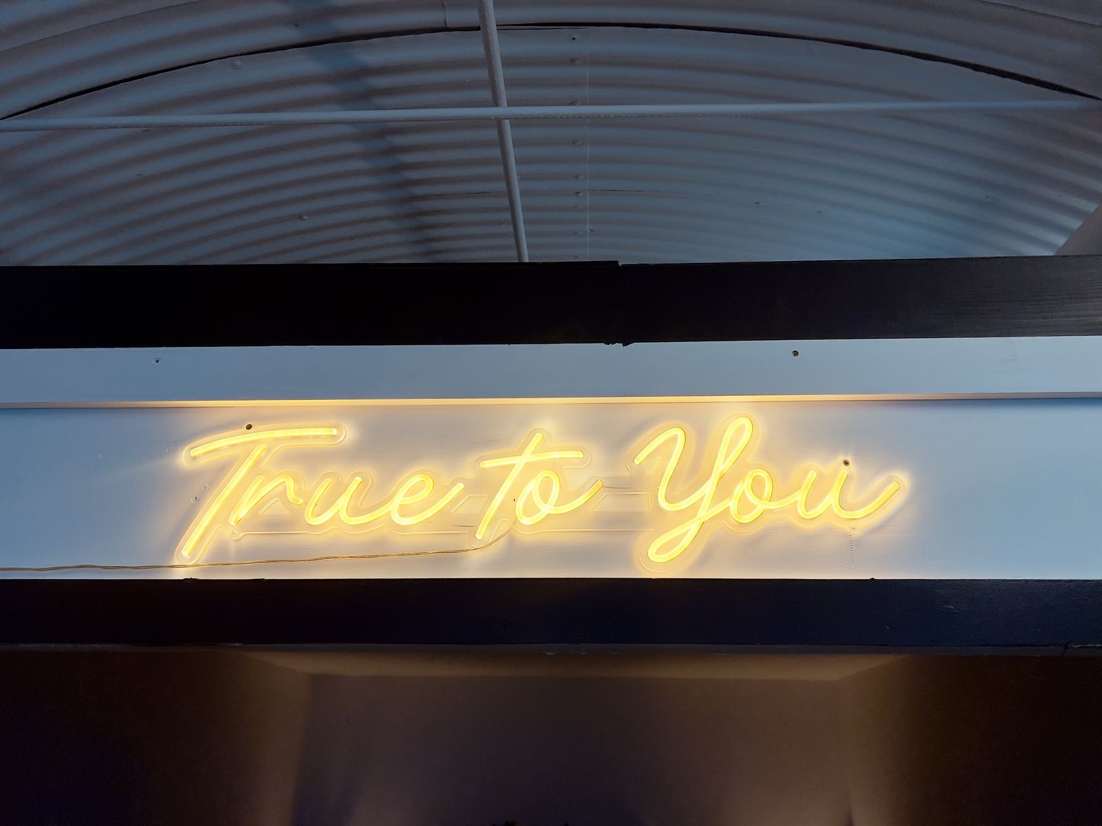 The True to You neon sign in warm yellow